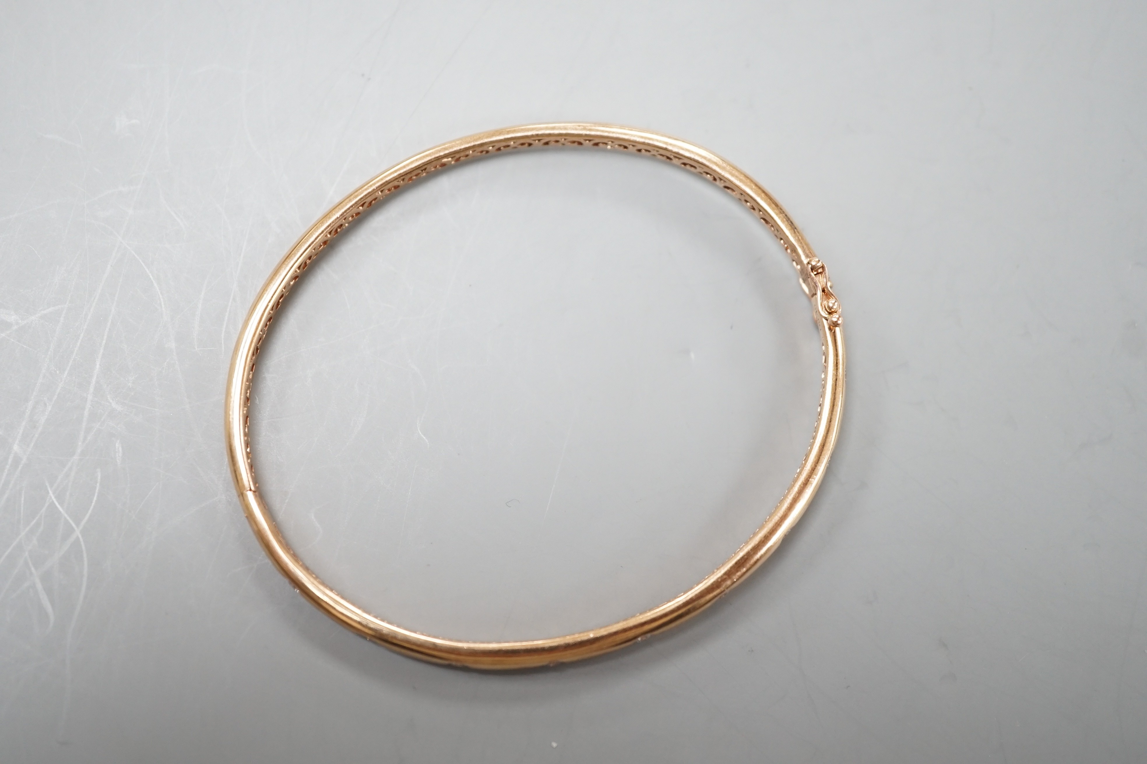A modern 9k and nine stone gypsy set diamond hinged bangle, interior diameter 60mm, gross weight 9.3 grams.